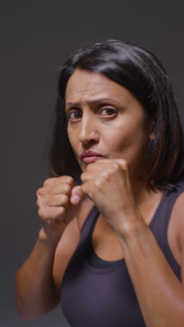 Vertical-Video-Studio-Portrait-Of-Mature-Woman-Wearing-Gym-Fitness-Clothing-Exercising-Sparring-At-Camera